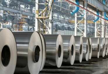 Row of rolls of aluminum lie in production shop of plant.