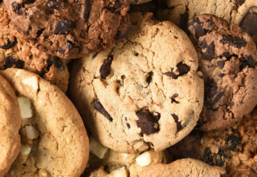 Closeup of a group of assorted cookies. Chocolate chip, oatmeal raisin, white chocolate fill the frame.