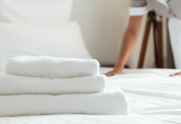 Young hotel maid making the bed with clean fresh towels