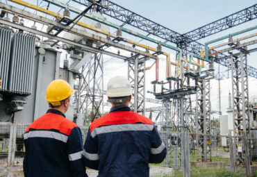 Two specialist electrical substation engineers inspect modern high-voltage equipment. Energy. Industry