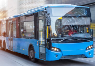 Blue bus moving on the road in city in early morning