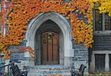 entrance to old ivy covered gothic stone college building with fall colors