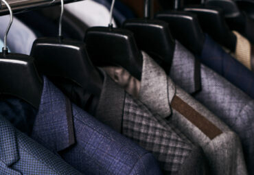 Mens suits in different colors hanging on hanger in a retail clothes store, close-up