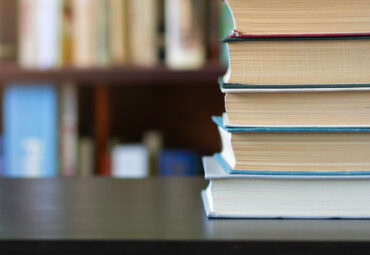 A stack of books on the background of bookshelves.