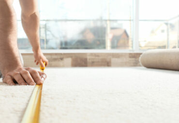 Man measuring carpet indoors. Construction tool