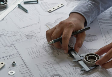 Engineer technician designing drawings mechanical parts engineering Engine
manufacturing factory Industry Industrial work project blueprints measuring bearings caliper tools