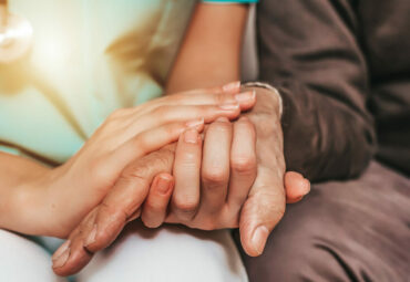 Cropped shot of a female carer consoling a senior patient at the nursing home. Closeup shot of a young woman holding a senior man's hands in comfort. Female healthcare worker holding hands of senior man at care home