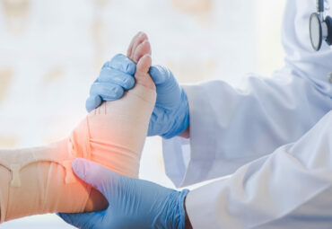 Close-up of pictures of a male orthopedic doctor or orthopedic doctor Wear a medical mask and medical gloves. Going to analyze the cause of ankle bone degeneration In his office at the hospital