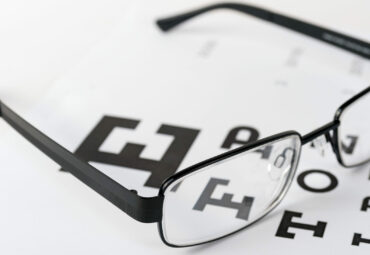 Eye glasses on eyesight test chart background close up