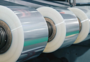 roll of plastic packaging film on the automatic packing machine in food product factory. industrial and technology concept. vintage photo and film style.